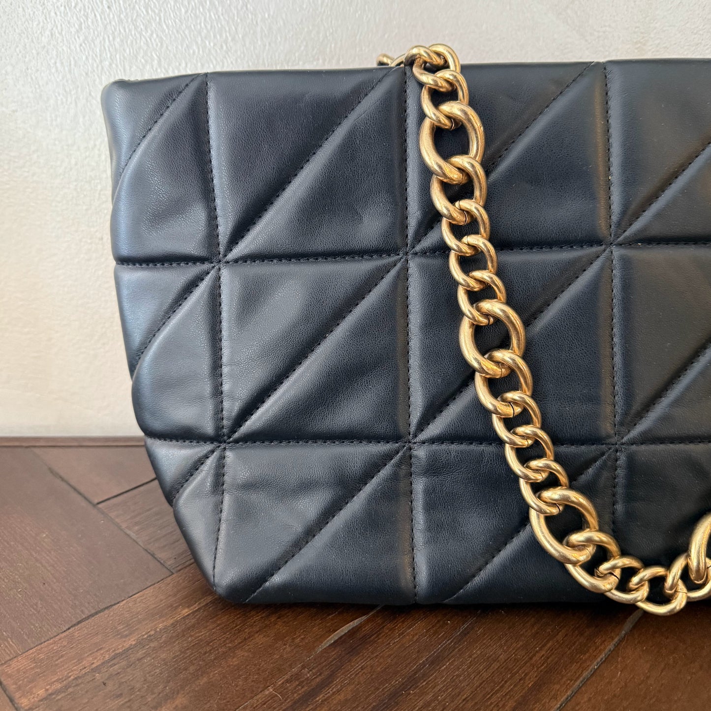 Bolso acolchado con asas de cadena dorada.