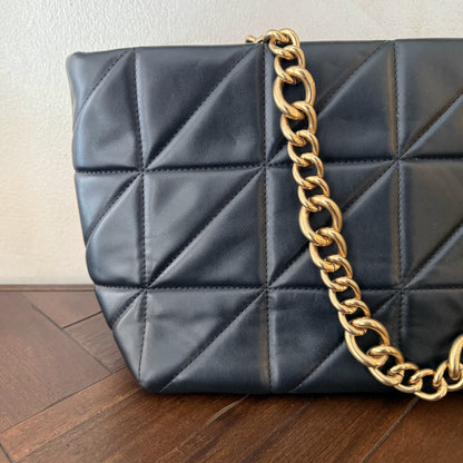 Bolso acolchado con asas de cadena dorada.