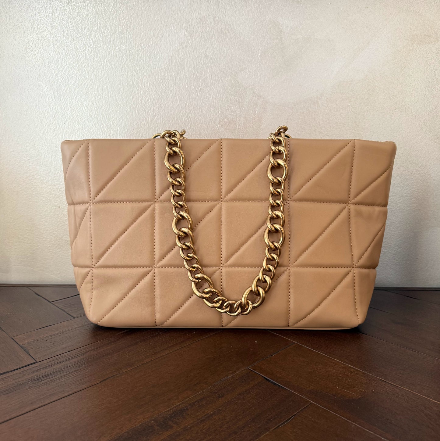 Bolso acolchado con asas de cadena dorada.