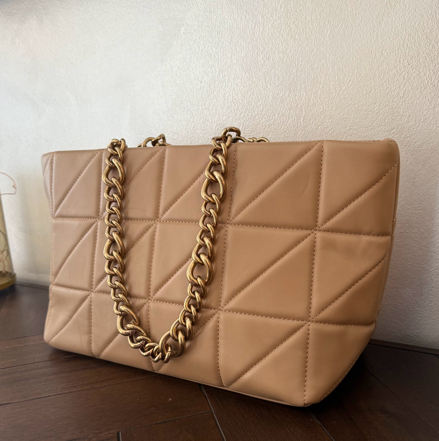 Bolso acolchado con asas de cadena dorada.