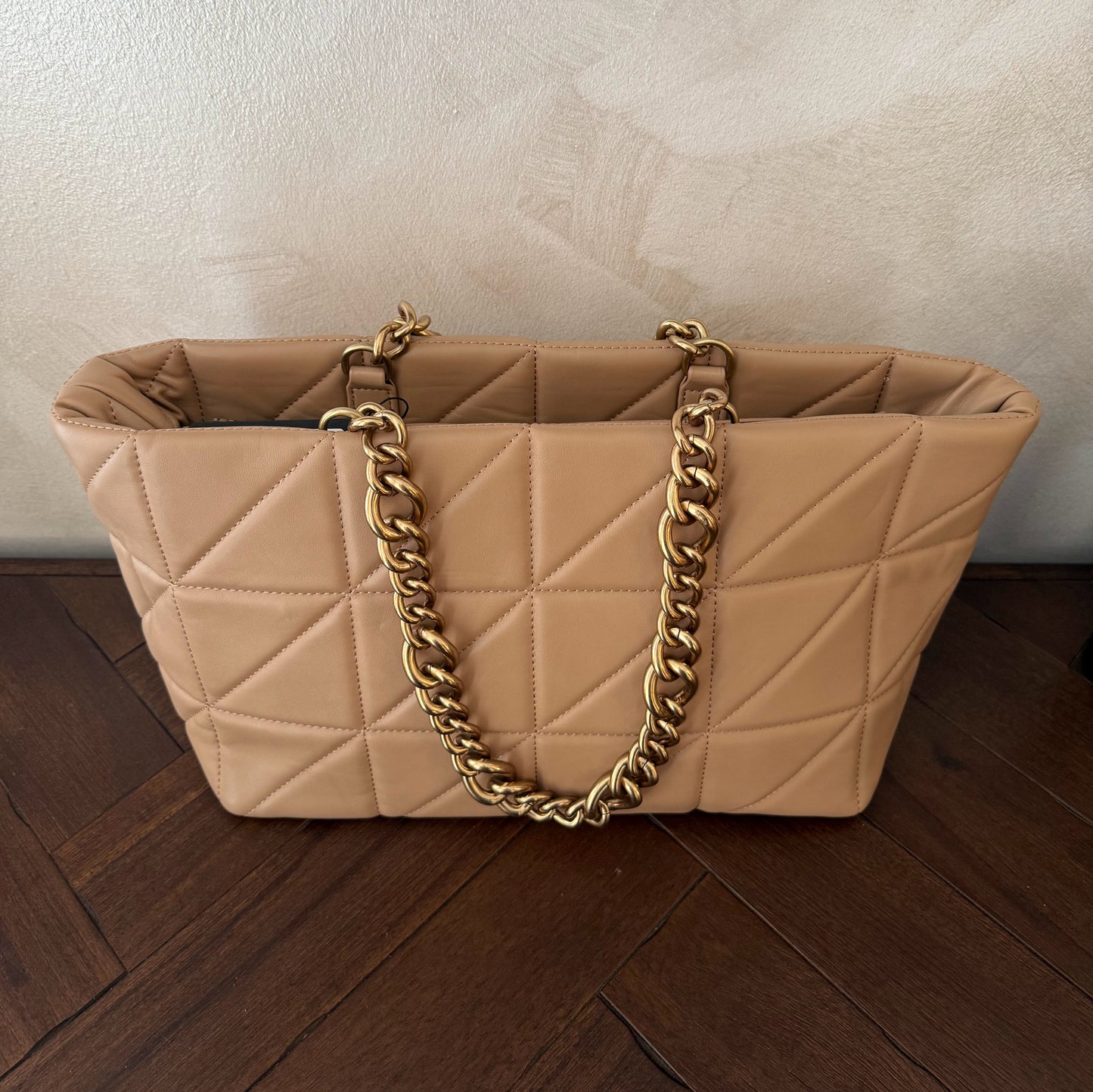 Bolso acolchado con asas de cadena dorada.