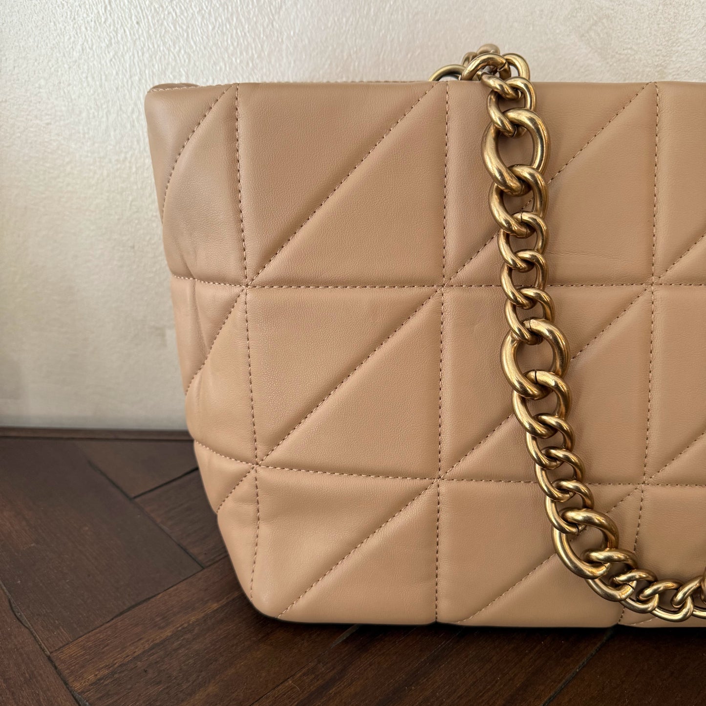 Bolso acolchado con asas de cadena dorada.
