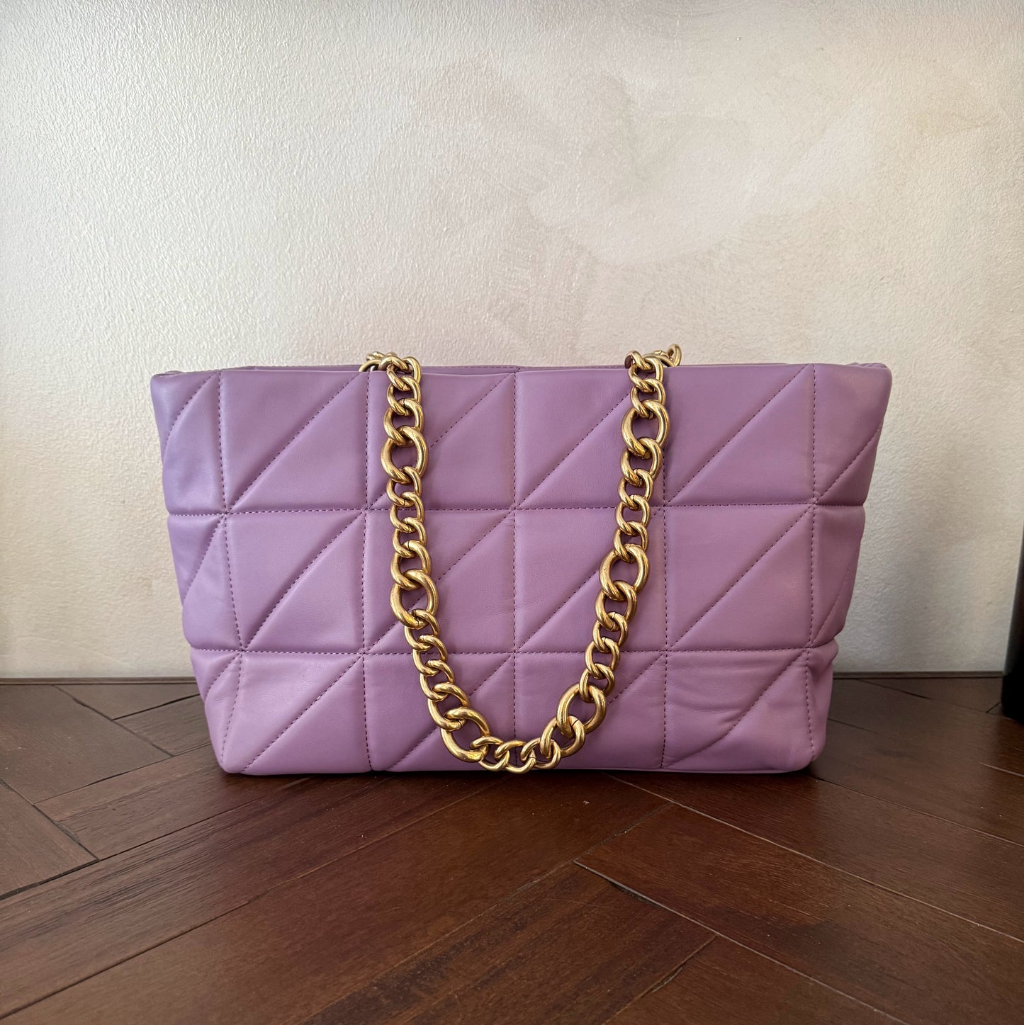 Bolso acolchado con asas de cadena dorada.