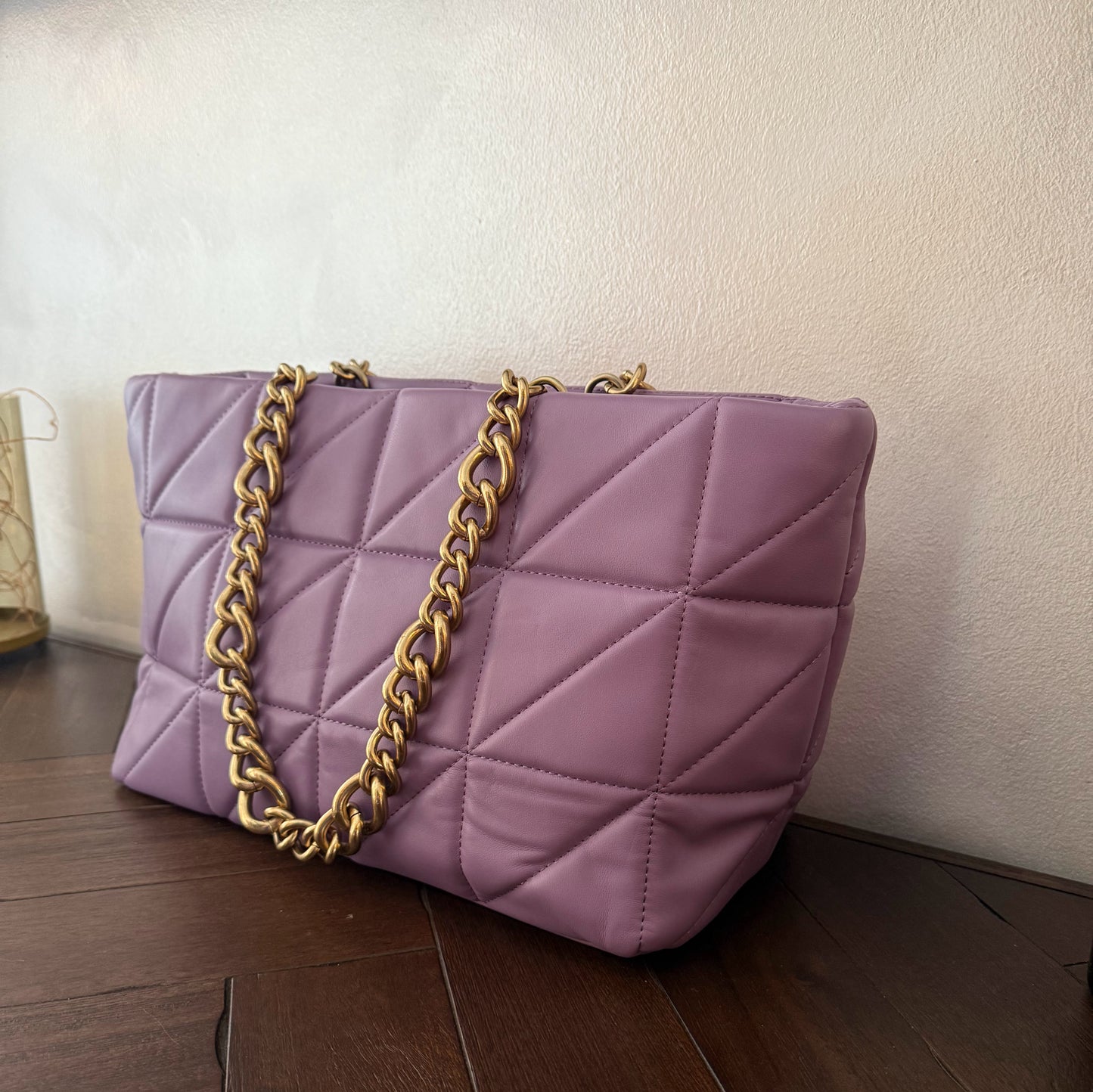 Bolso acolchado con asas de cadena dorada.