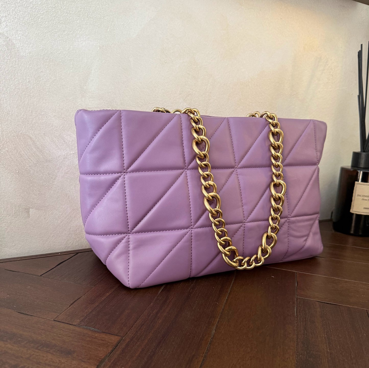 Bolso acolchado con asas de cadena dorada.