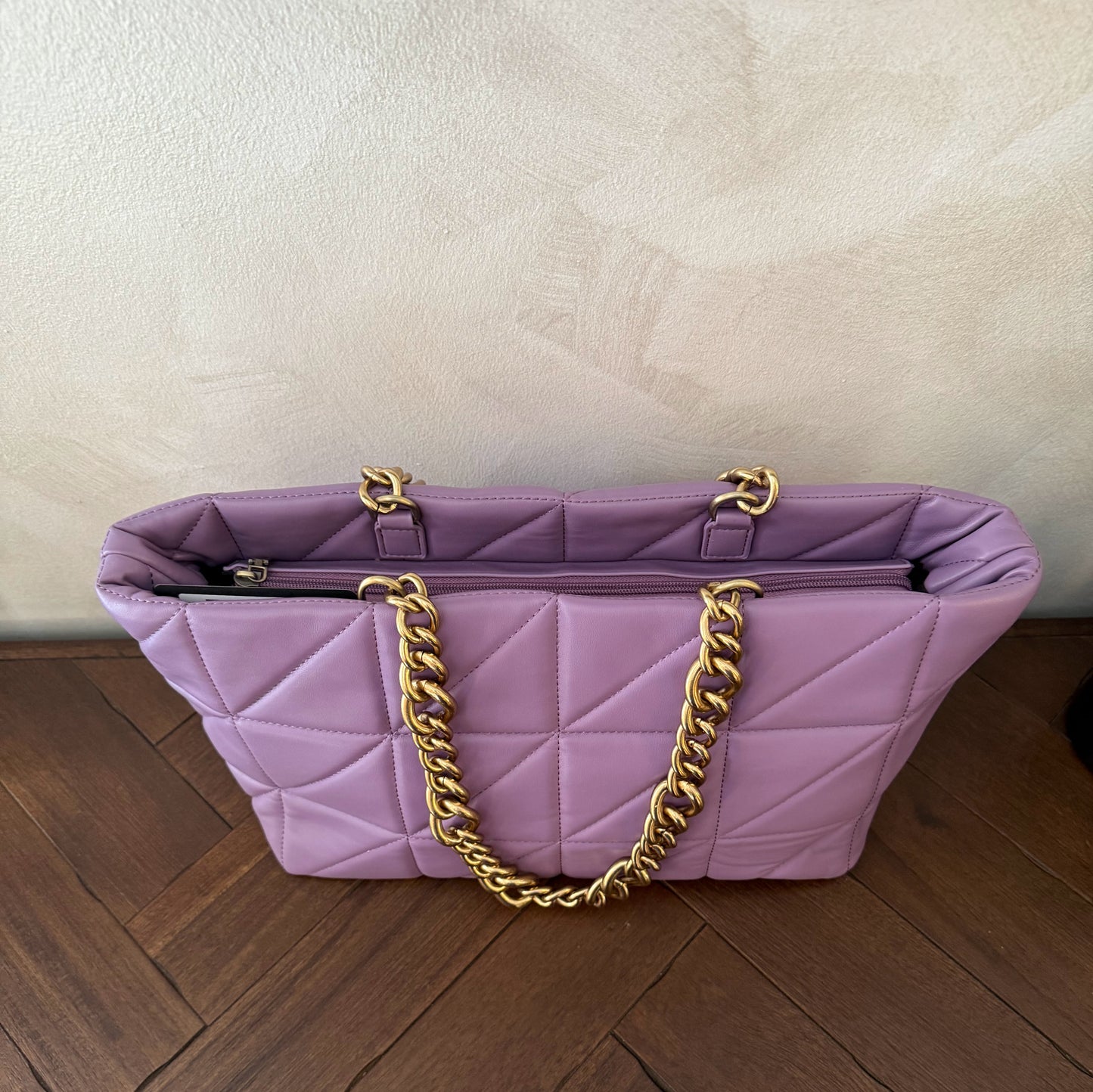 Bolso acolchado con asas de cadena dorada.