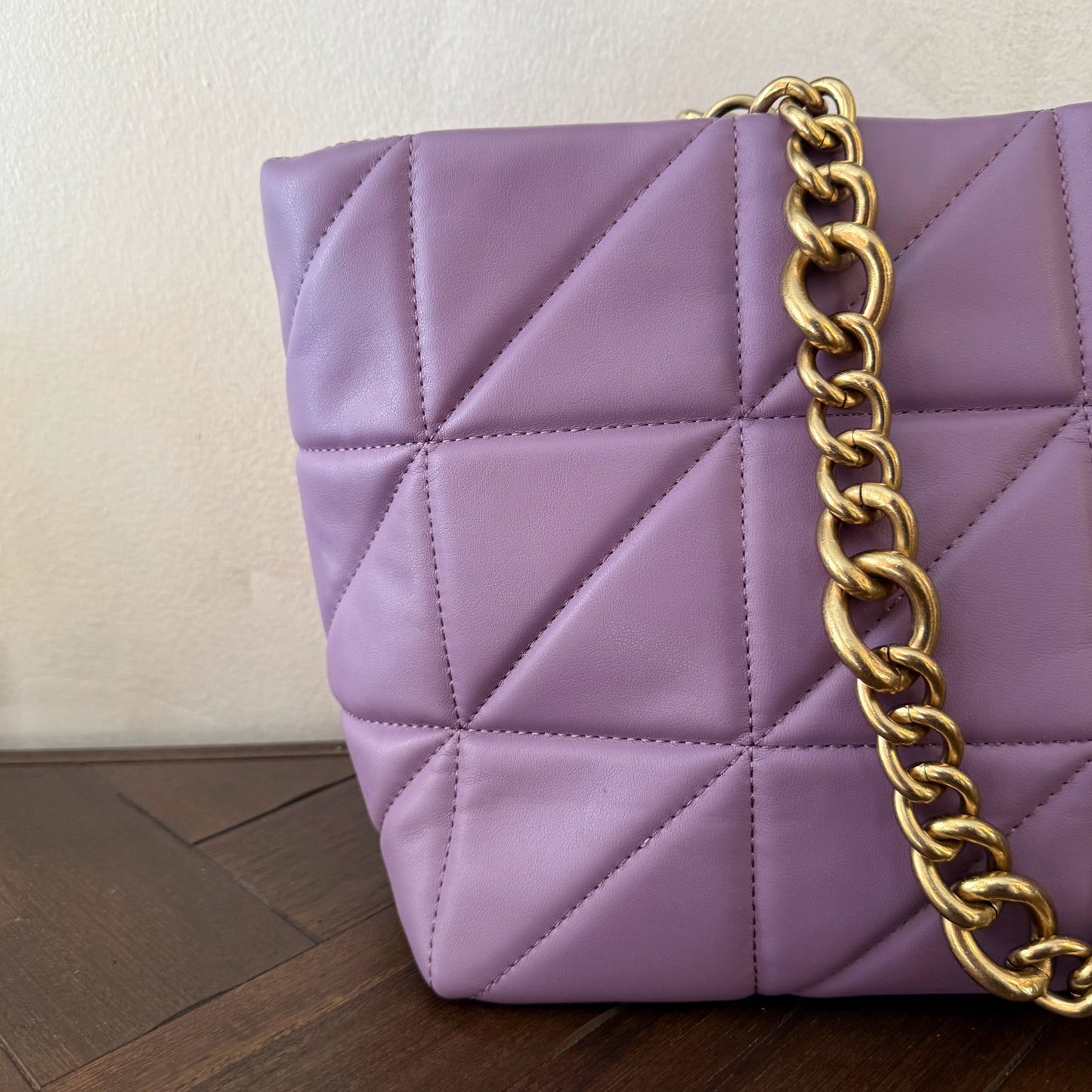 Bolso acolchado con asas de cadena dorada.