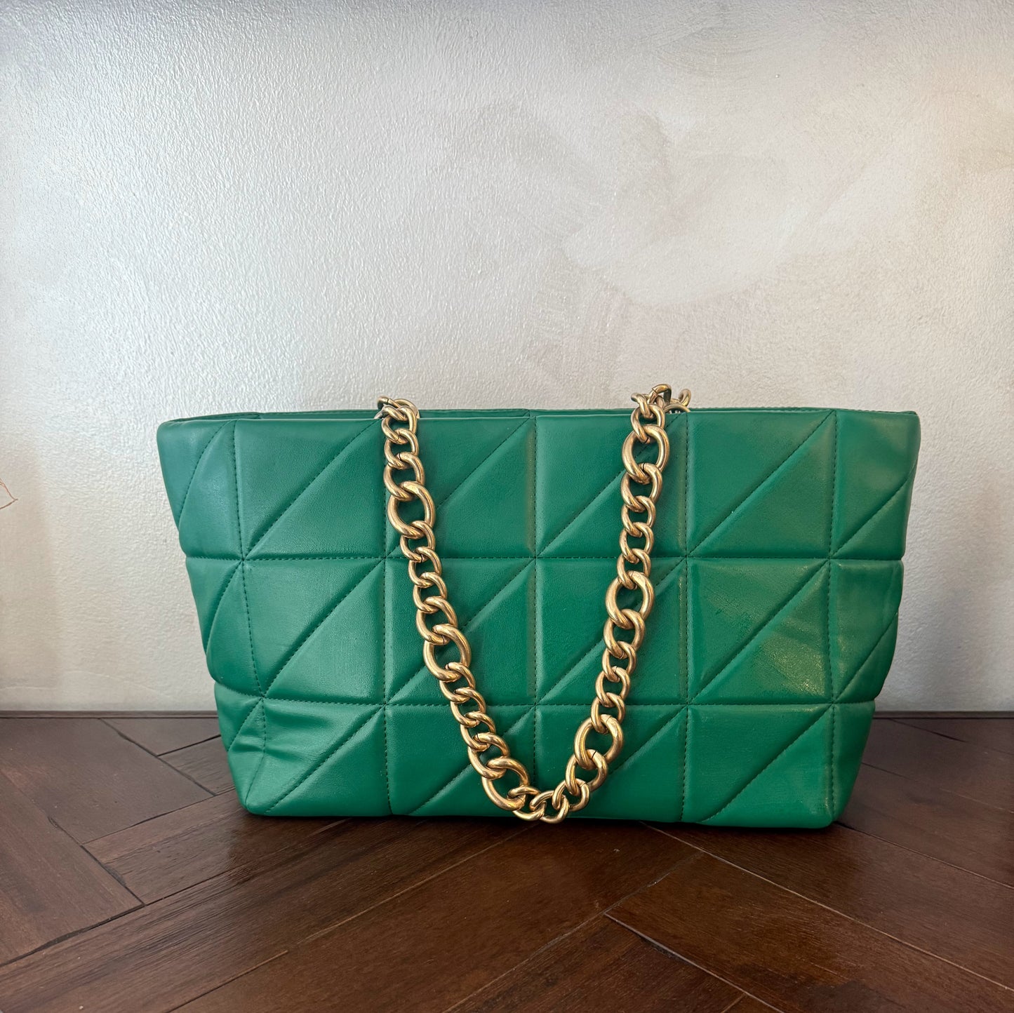 Bolso acolchado con asas de cadena dorada.