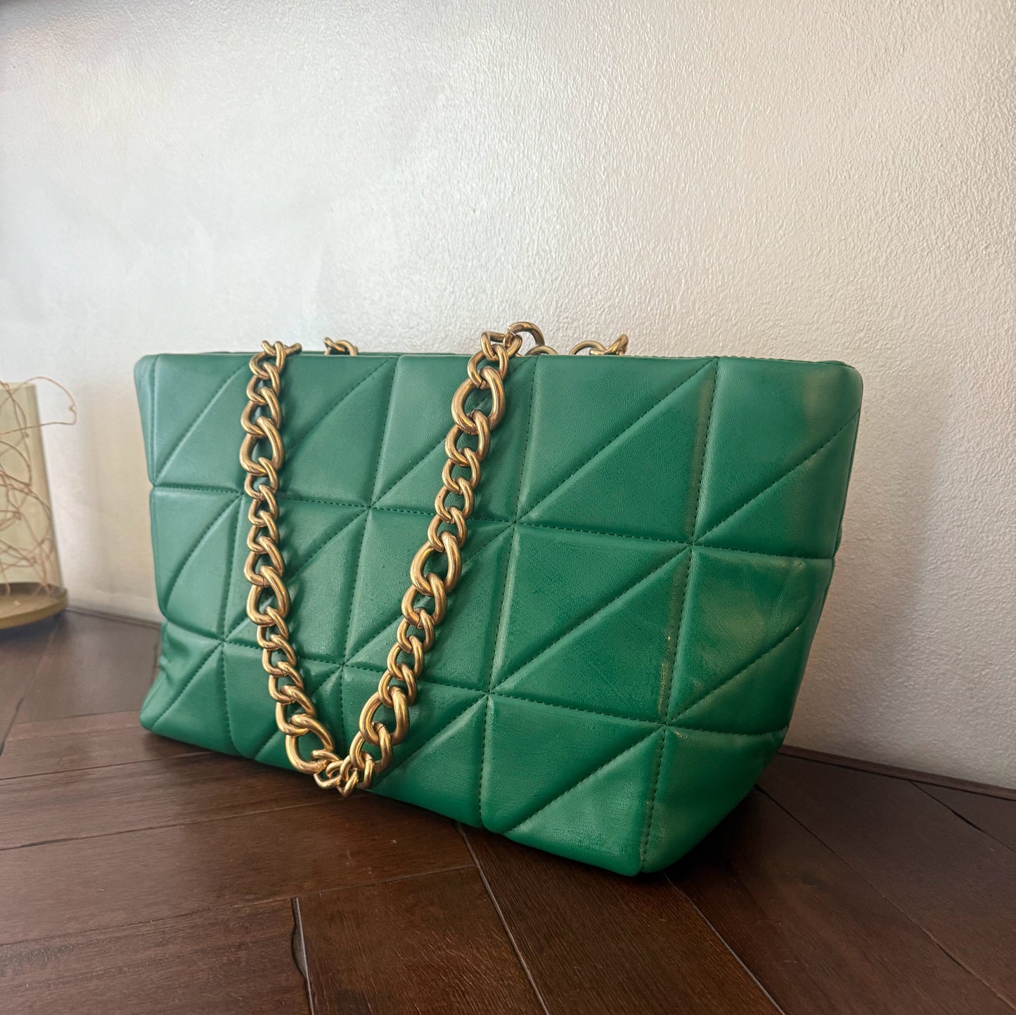 Bolso acolchado con asas de cadena dorada.