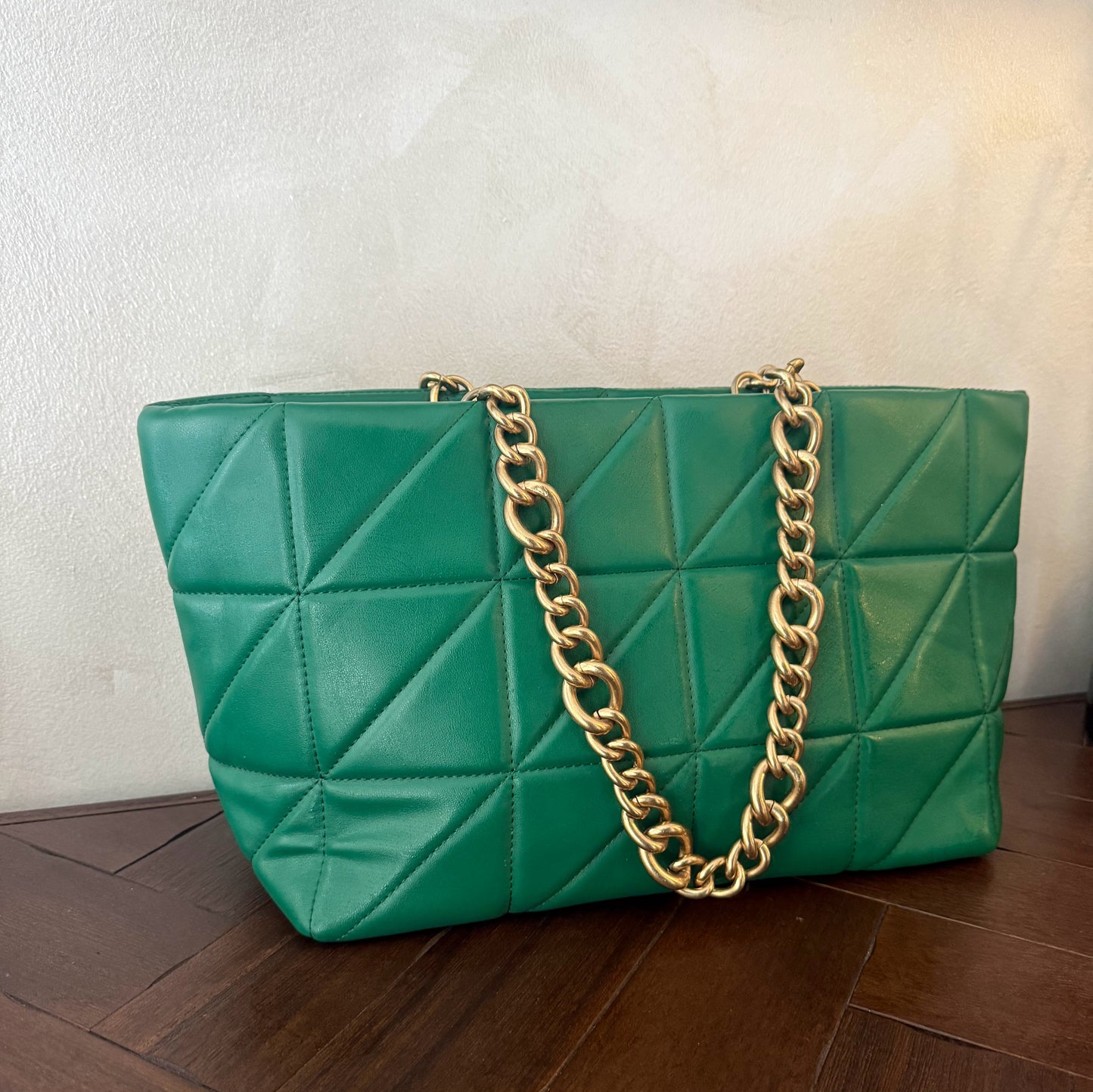 Bolso acolchado con asas de cadena dorada.
