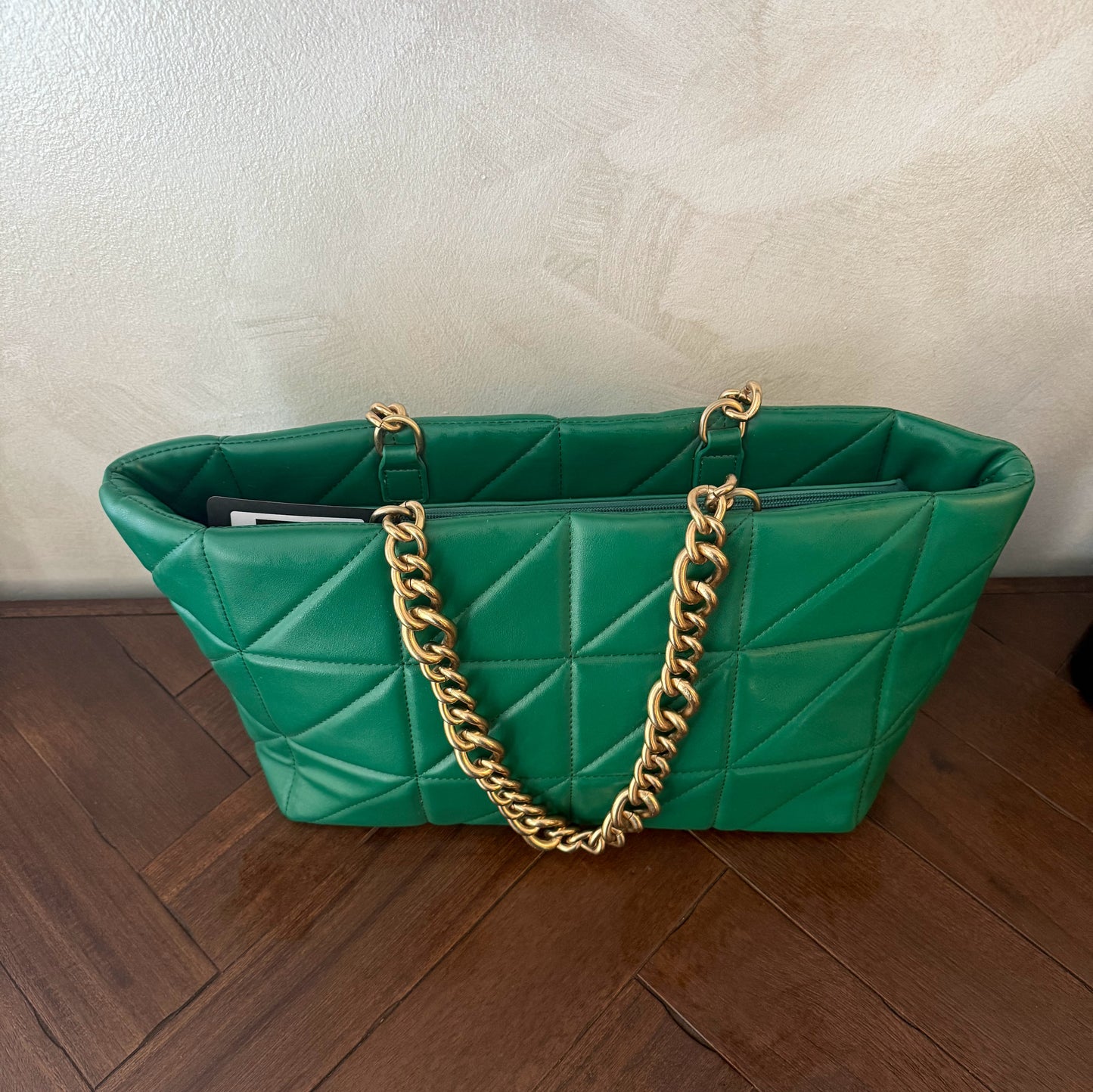 Bolso acolchado con asas de cadena dorada.
