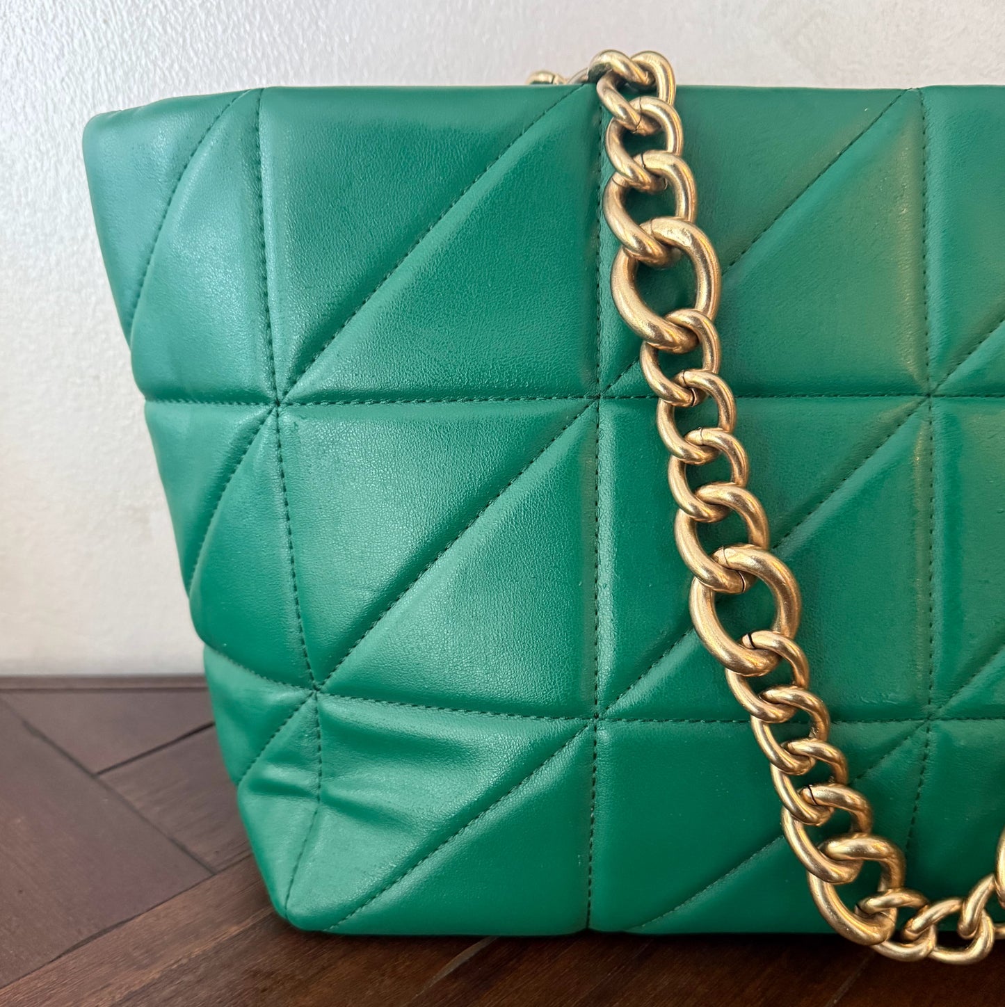 Bolso acolchado con asas de cadena dorada.