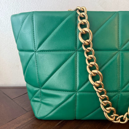 Bolso acolchado con asas de cadena dorada.