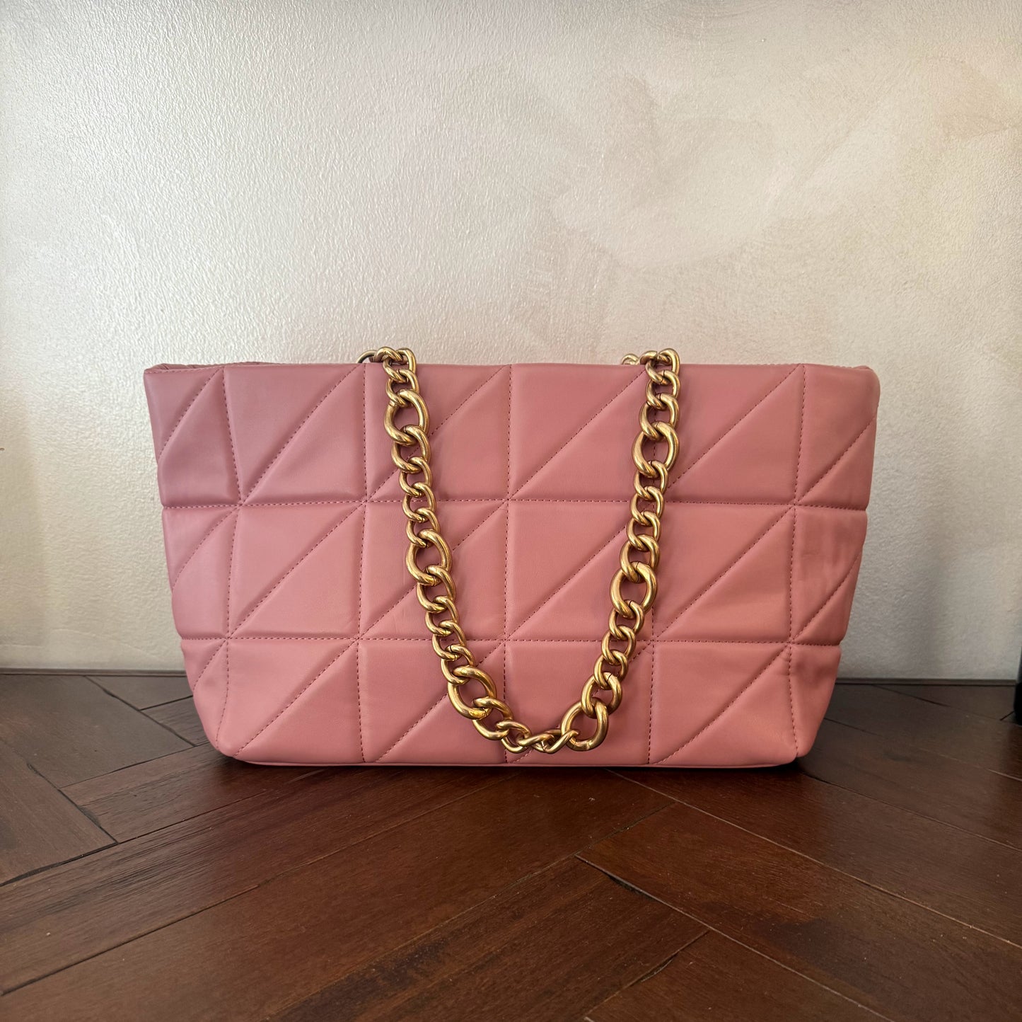 Bolso acolchado con asas de cadena dorada.