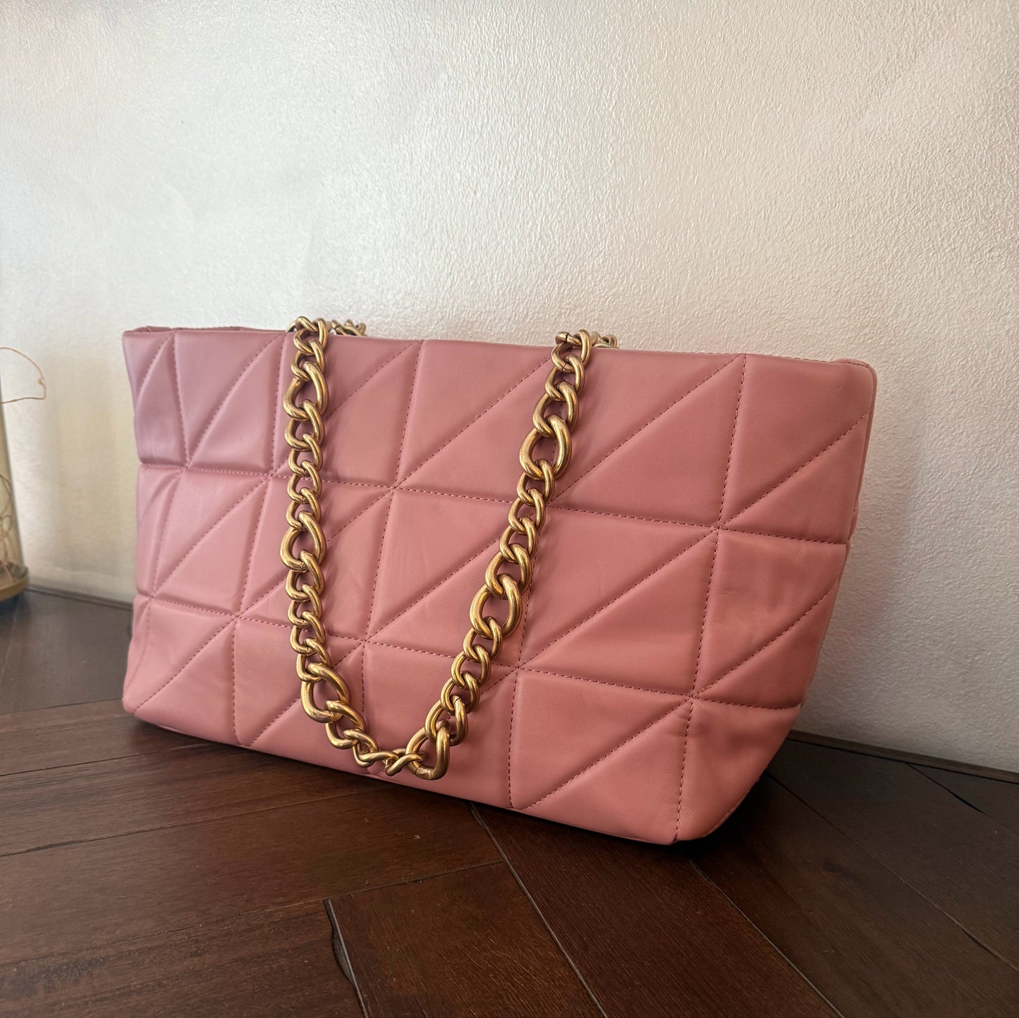 Bolso acolchado con asas de cadena dorada.