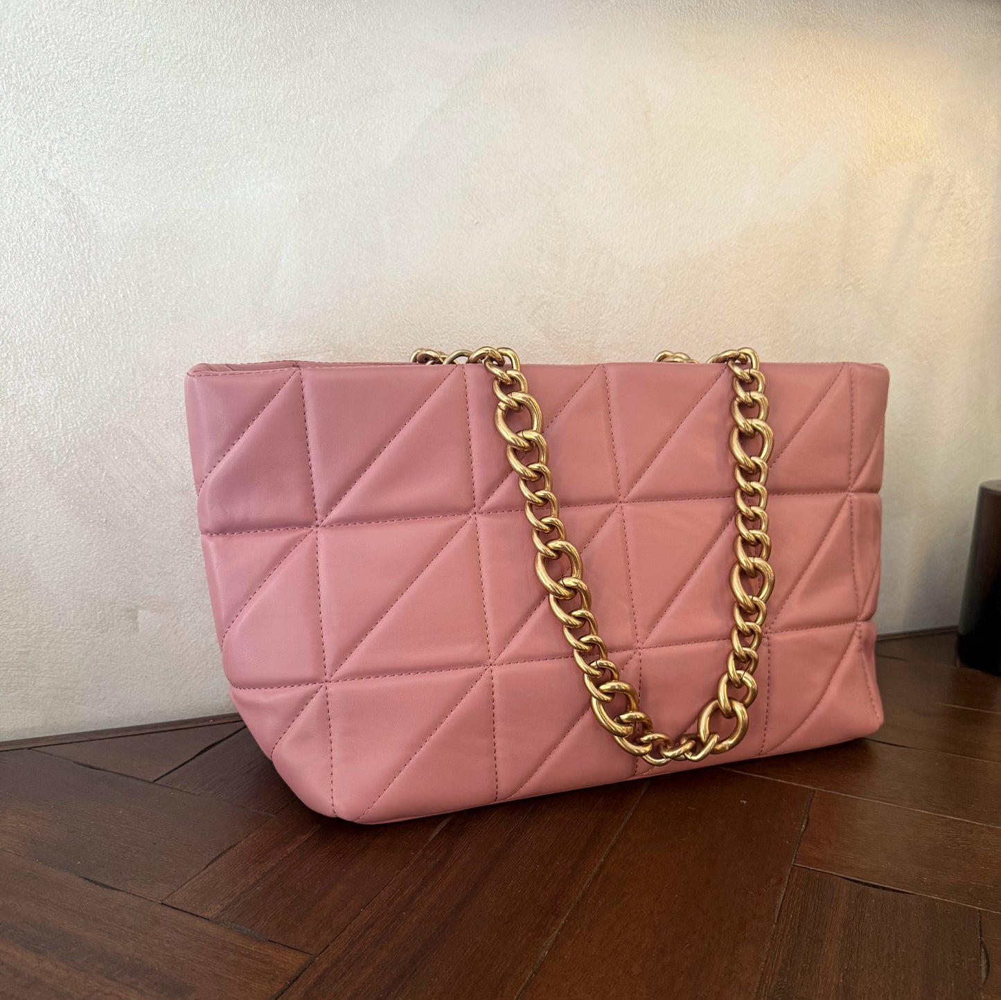 Bolso acolchado con asas de cadena dorada.