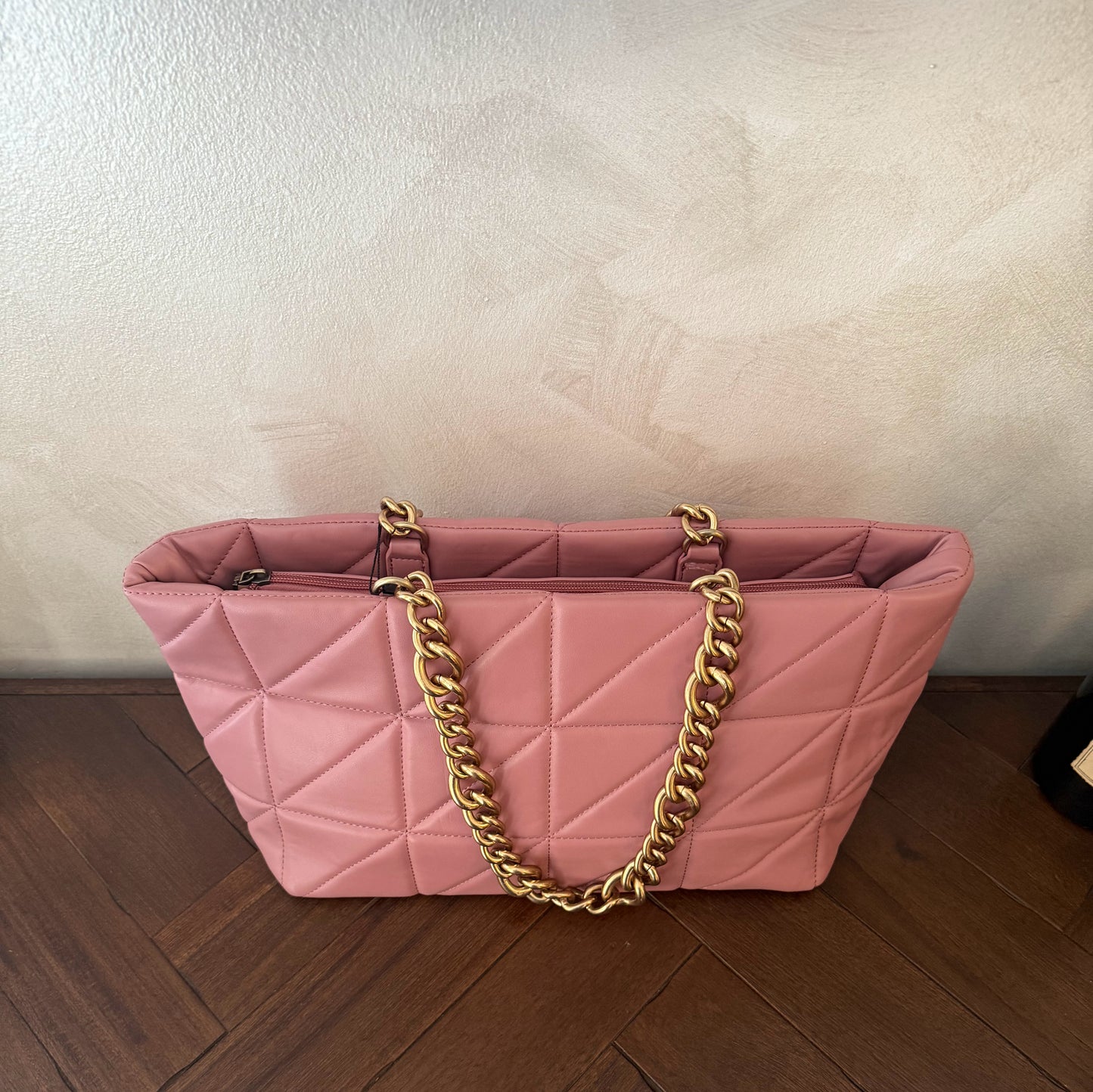Bolso acolchado con asas de cadena dorada.