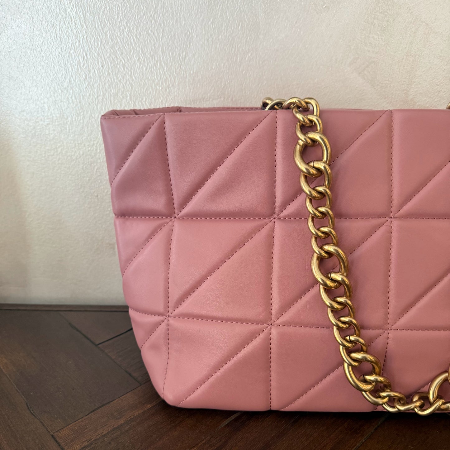 Bolso acolchado con asas de cadena dorada.