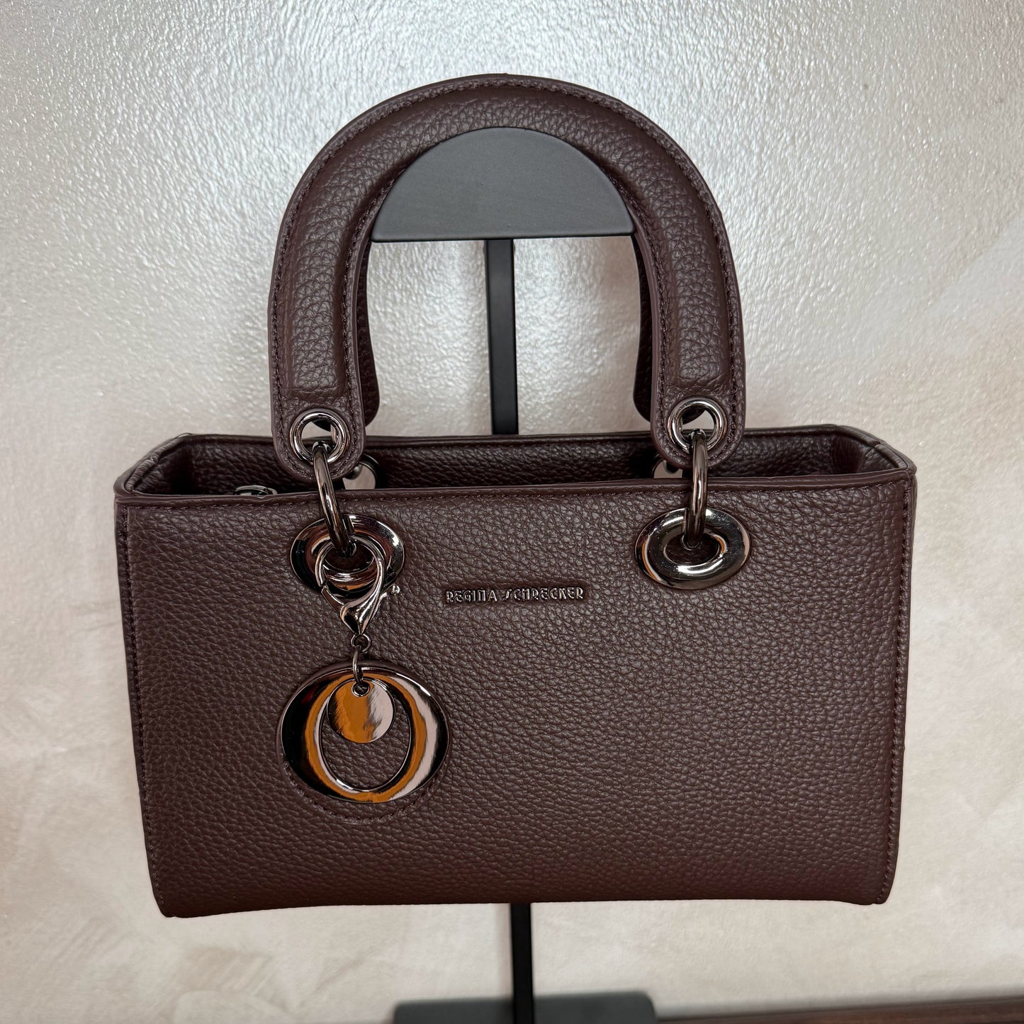 Bolso de mano con asa larga y colgante metálico