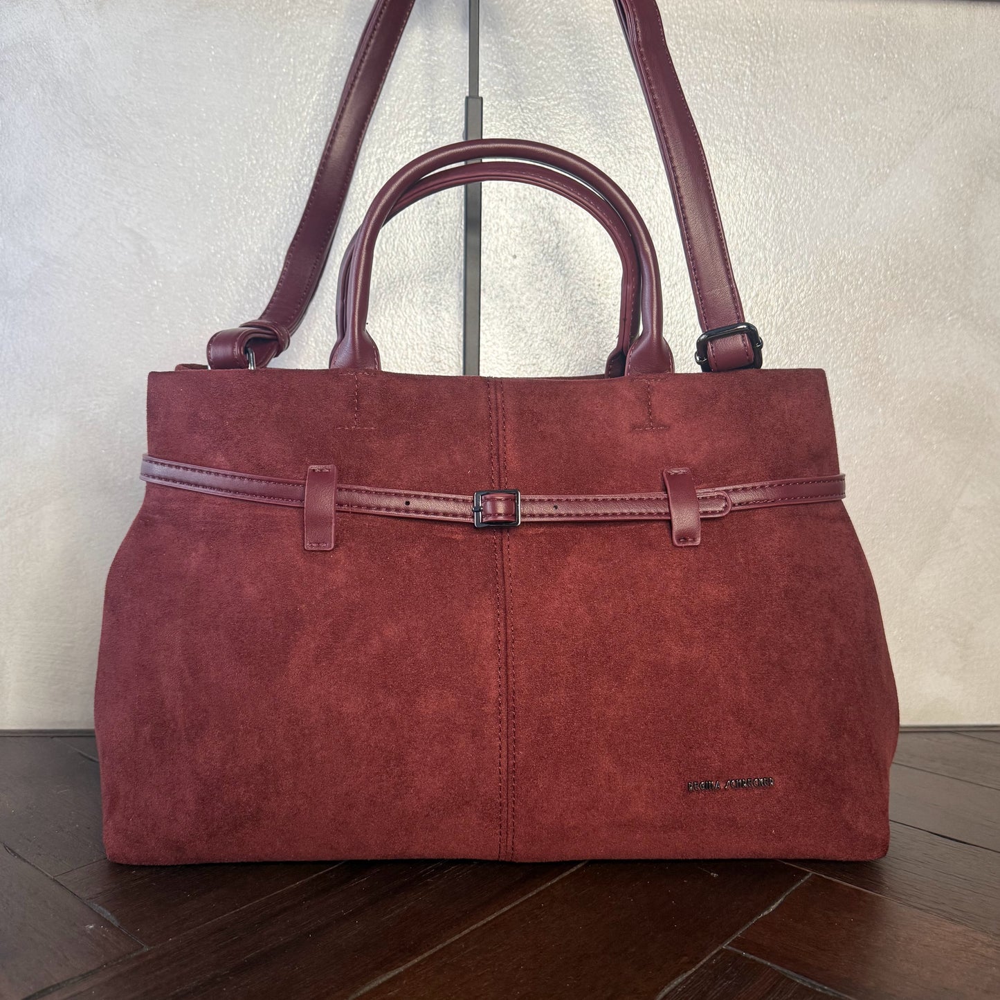 Bolso de mano de antelina elegante y sofisticado con asa larga.