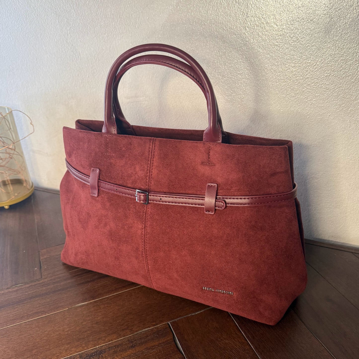 Bolso de mano de antelina elegante y sofisticado con asa larga.