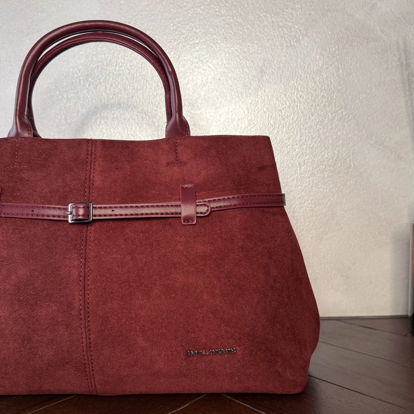 Bolso de mano de antelina elegante y sofisticado con asa larga.