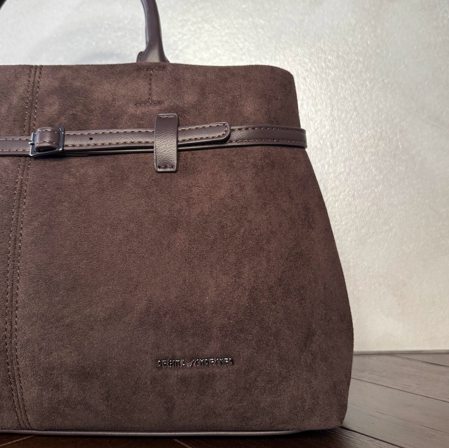 Bolso de mano de antelina elegante y sofisticado con asa larga.